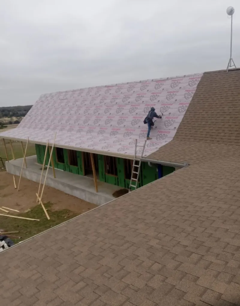 Worker preparing underlayment for a metal roof installation in Miramar Beach